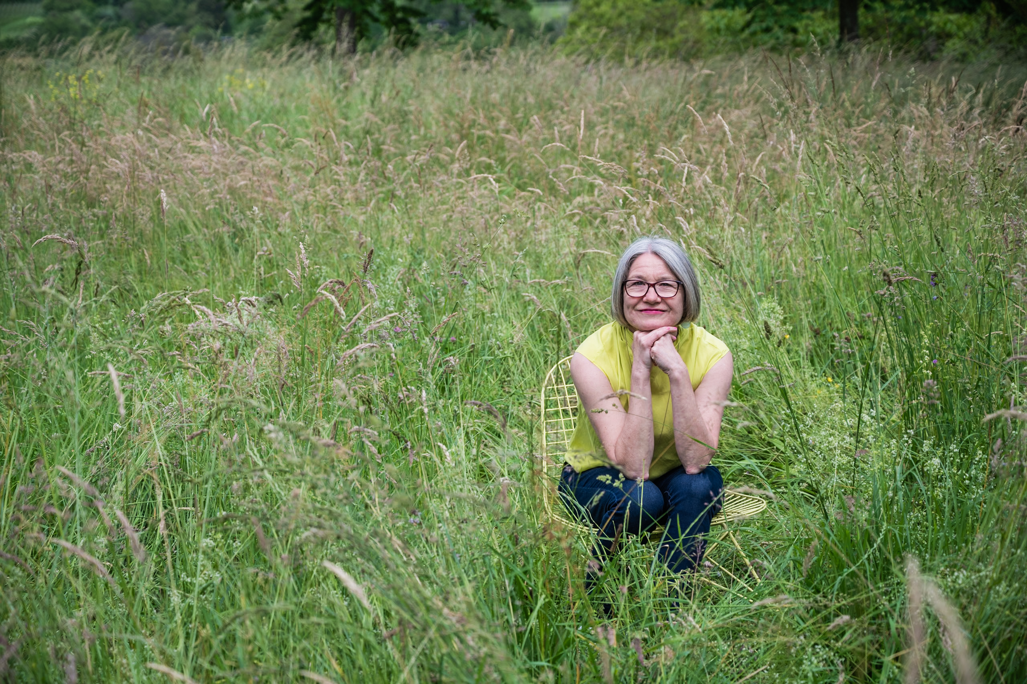 Portrait seated on a chair in a summer meadow, UK